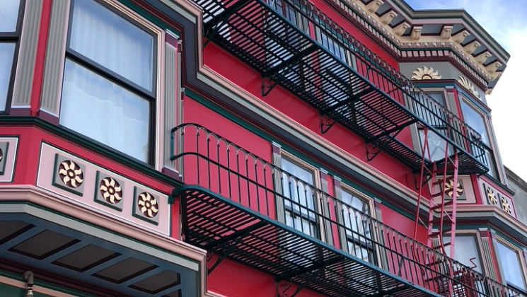 red victorian house with glass windows and some black iron corridors