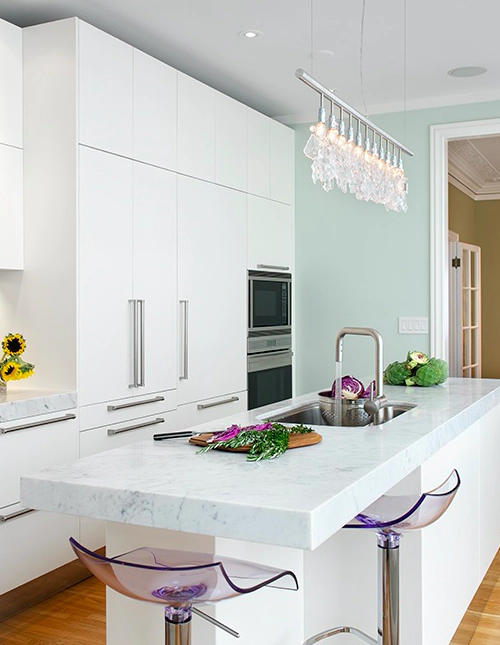 white kitchen with white cabinets and a white countertop with purple transparent chairs