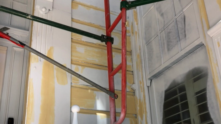 yellow drywall repair of a tall house with glass windows